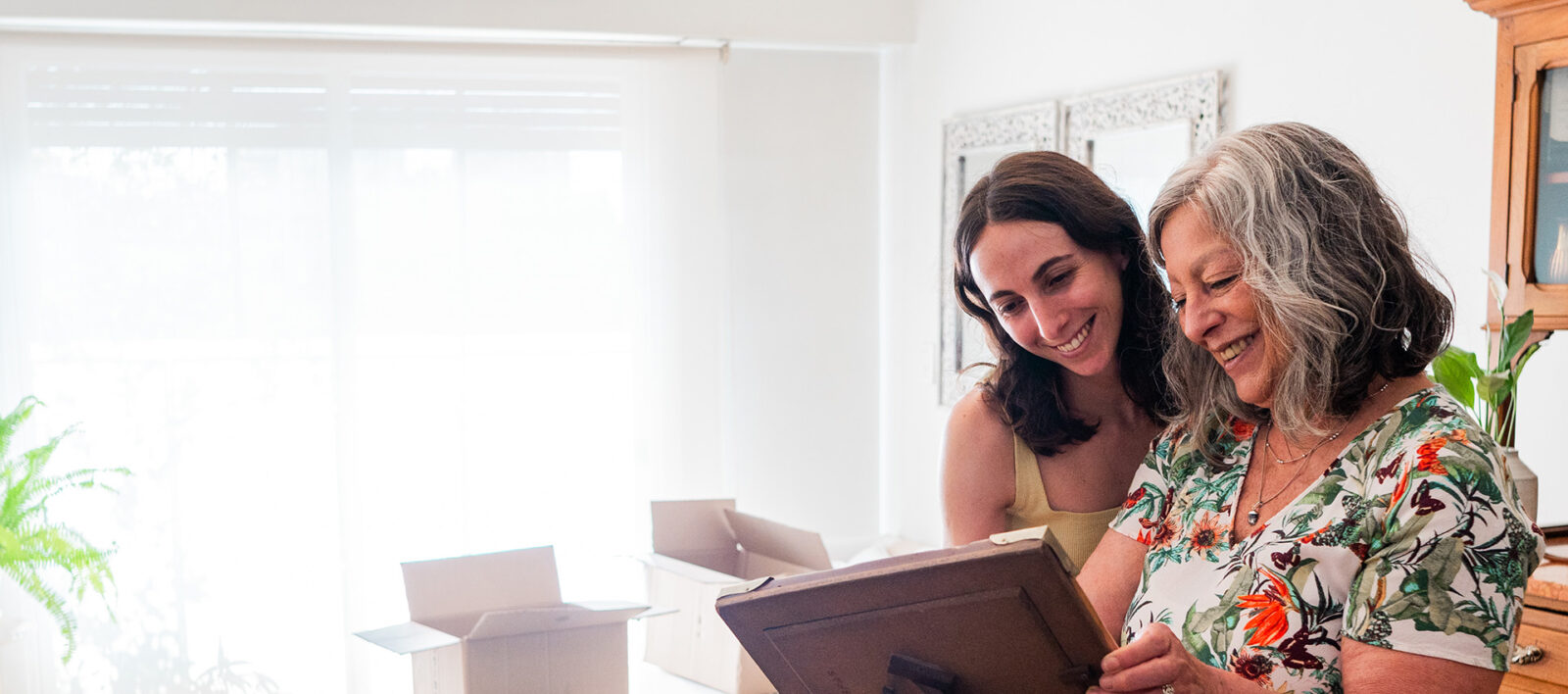 Mother showing picture frame to daughter while packing