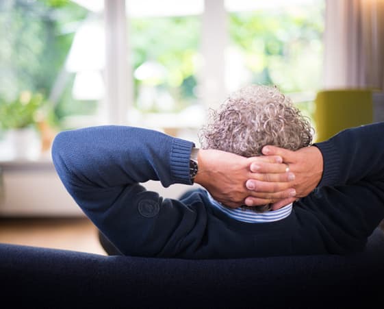 Person relaxing on a sofa, hands behind their head.